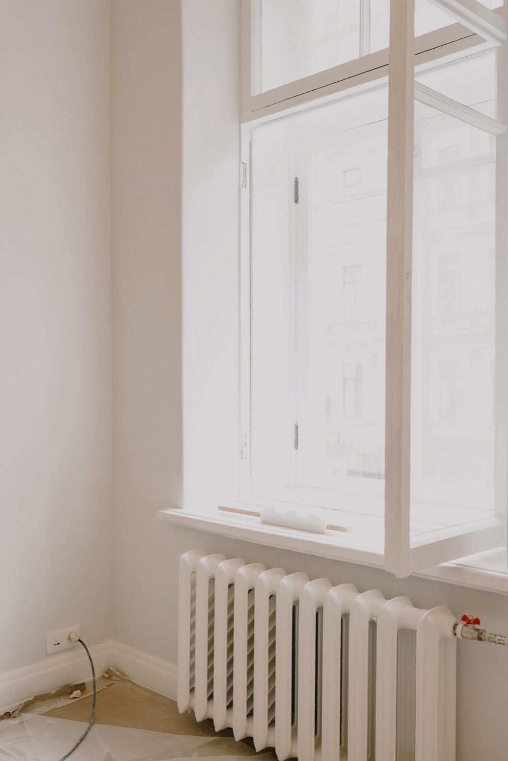 Radiateur en fonte blanc sous une fenêtre lumineuse